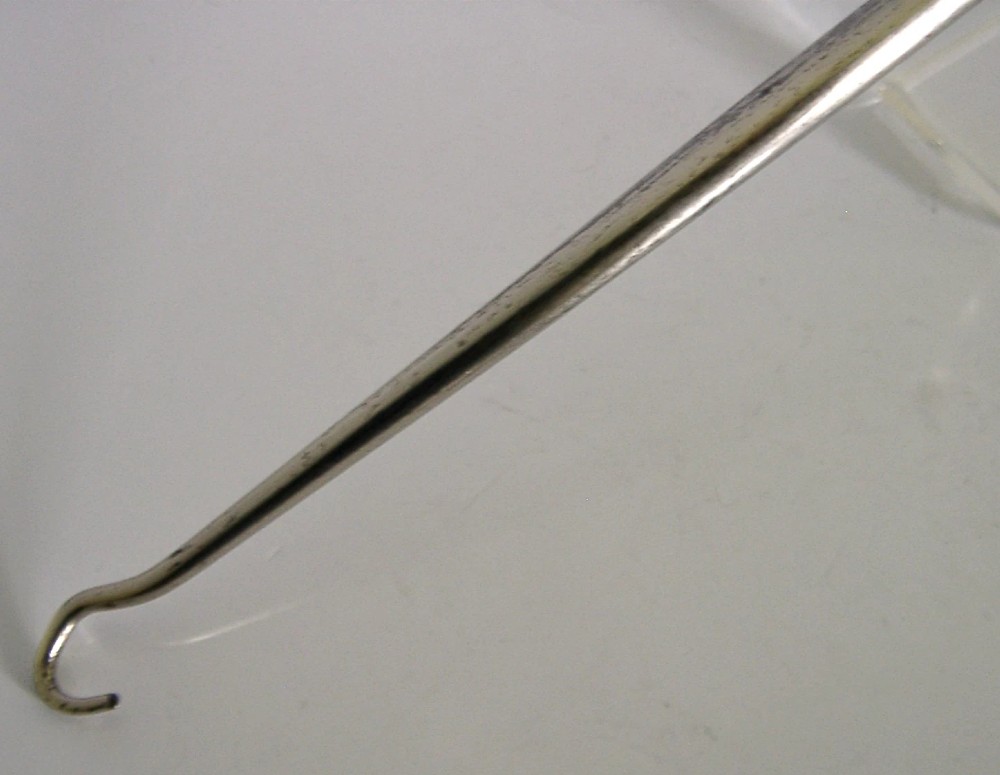 An Edwardian sterling silver button hook featuring a figurative teddy bear handle connected to a long steel shaft. View V
