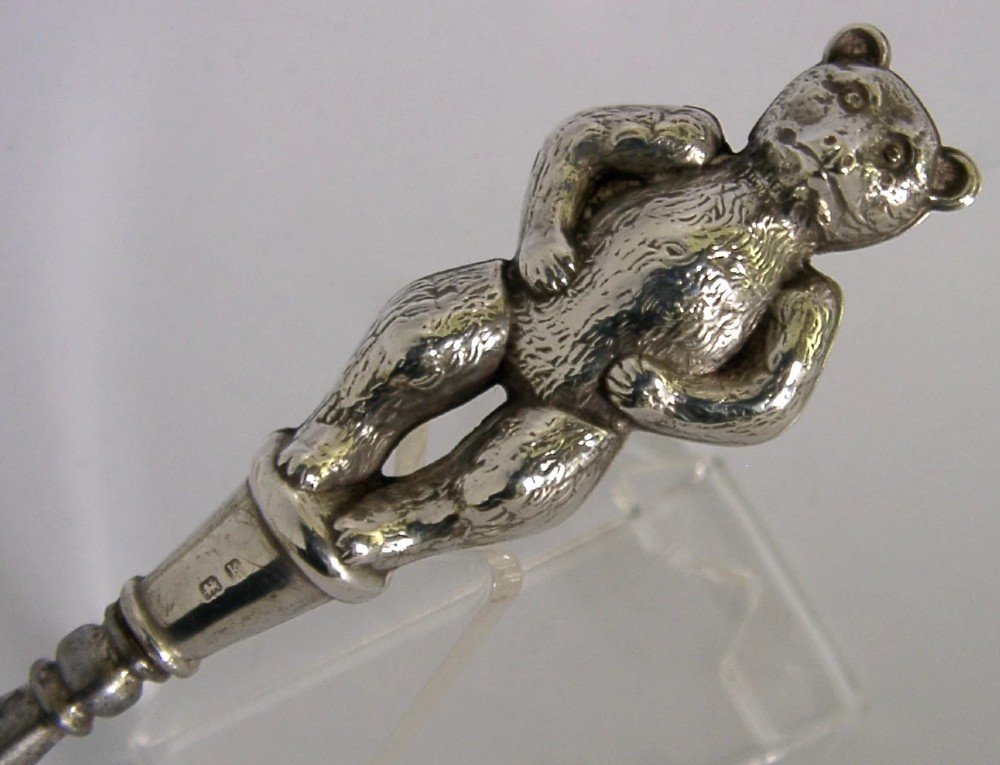 An Edwardian sterling silver button hook featuring a figurative teddy bear handle connected to a long steel shaft. View VI