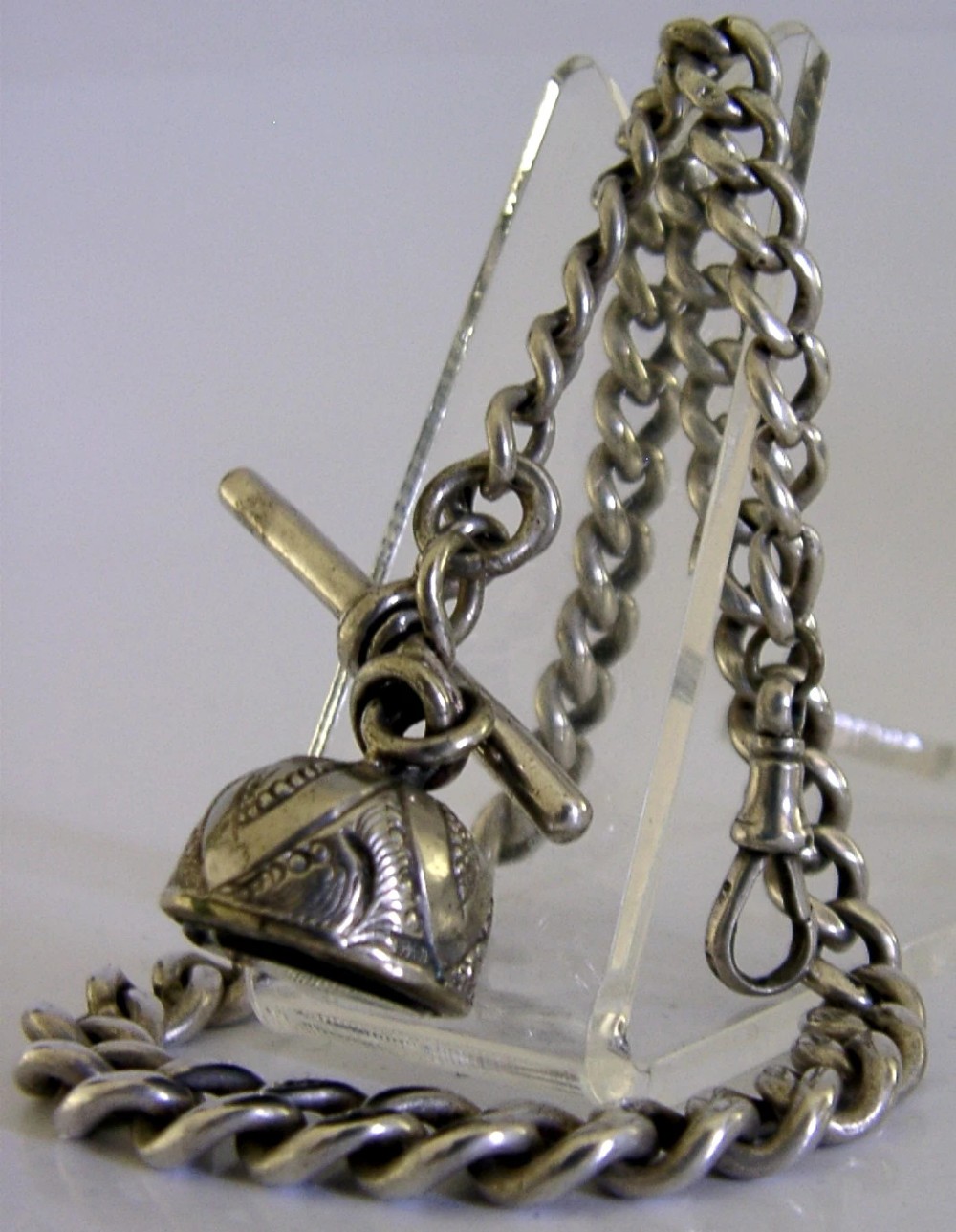 An Edwardian sterling silver curb-link pocket watch chain featuring a T-bar, swivel clip, and an engraved dome-shaped seal fob.