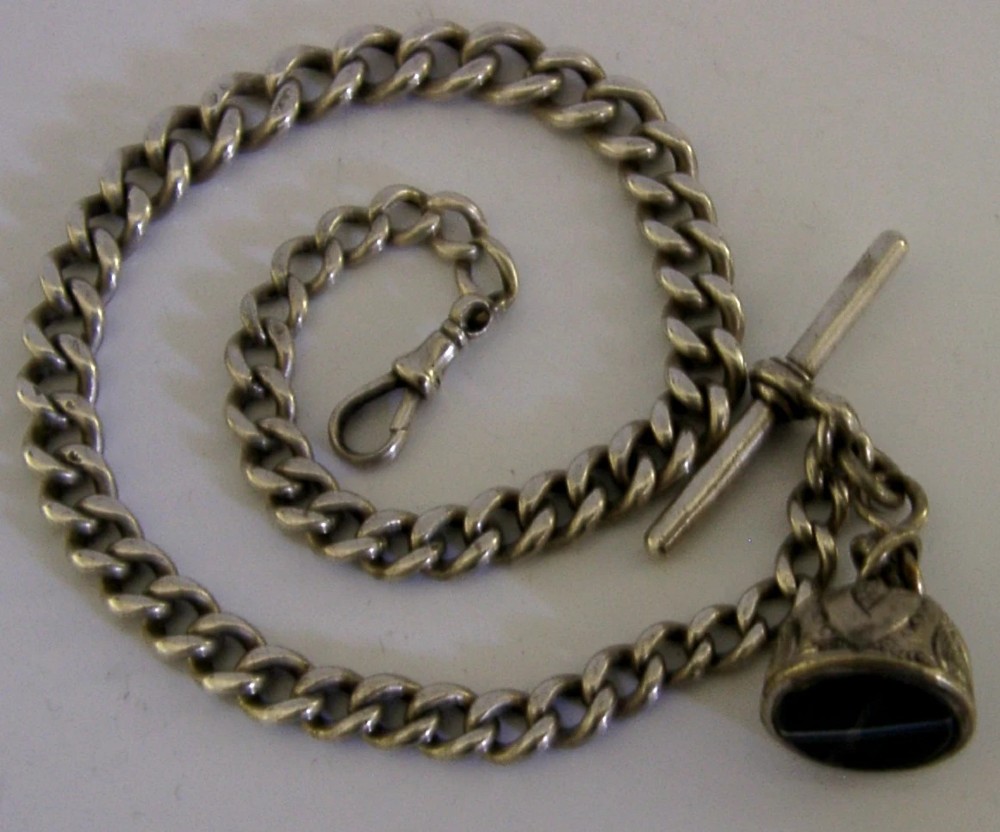 An Edwardian sterling silver curb-link pocket watch chain featuring a T-bar, swivel clip, and an engraved dome-shaped seal fob. View IV