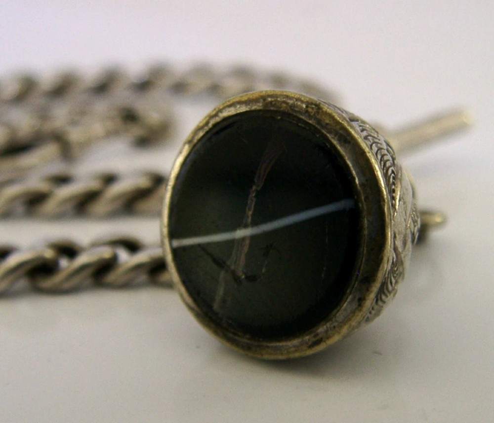 An Edwardian sterling silver curb-link pocket watch chain featuring a T-bar, swivel clip, and an engraved dome-shaped seal fob. View V