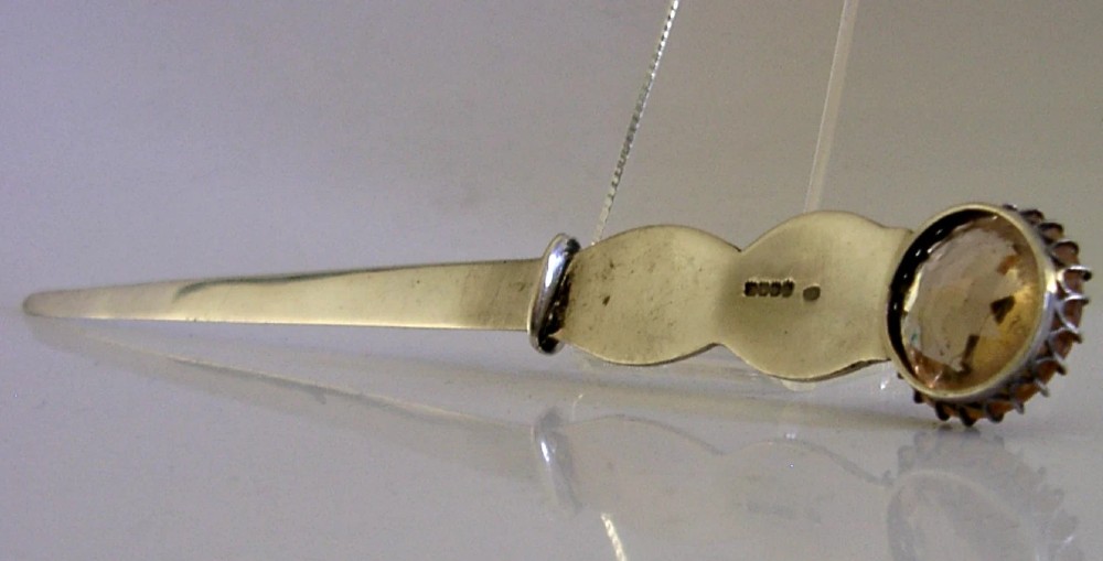 A Scottish sterling silver letter opener featuring Celtic interlace carving and an amber-toned citrine gem on the handle. View V