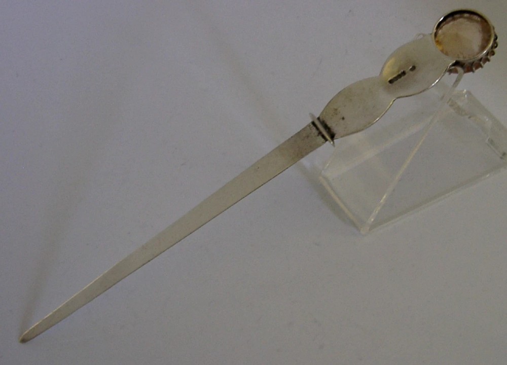 A Scottish sterling silver letter opener featuring Celtic interlace carving and an amber-toned citrine gem on the handle. View VI