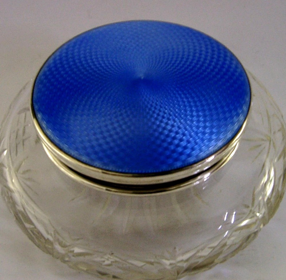 An Art Deco cut glass vanity jar featuring a sterling silver lid with royal blue engine-turned guilloche enamel.