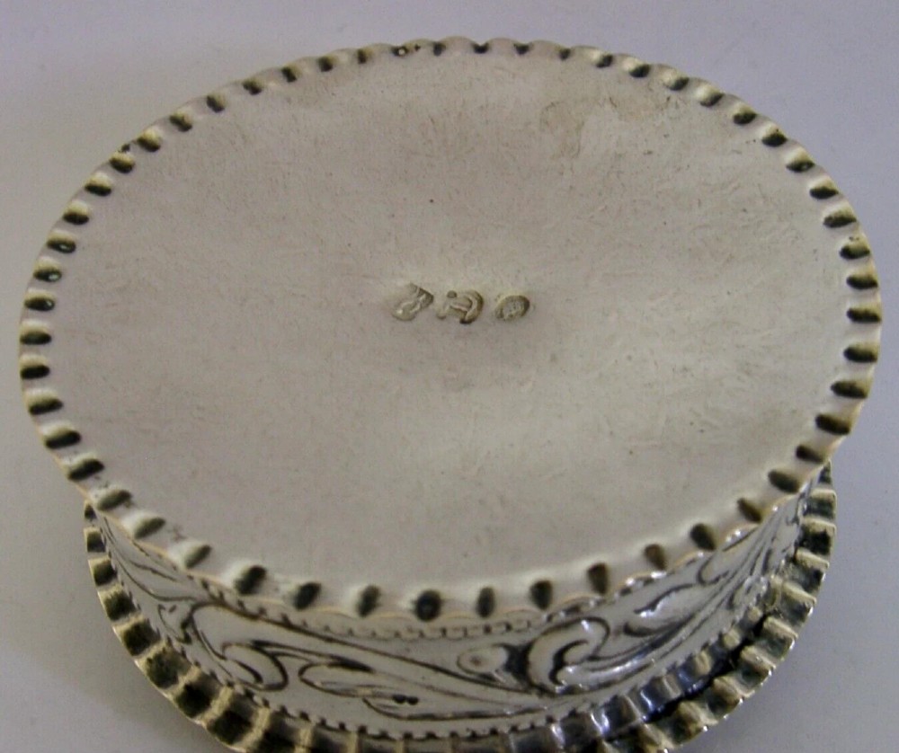 A circular solid silver table box featuring embossed repousse detail of a castle scene framed by acanthus scrolls and fluted edges. View IX
