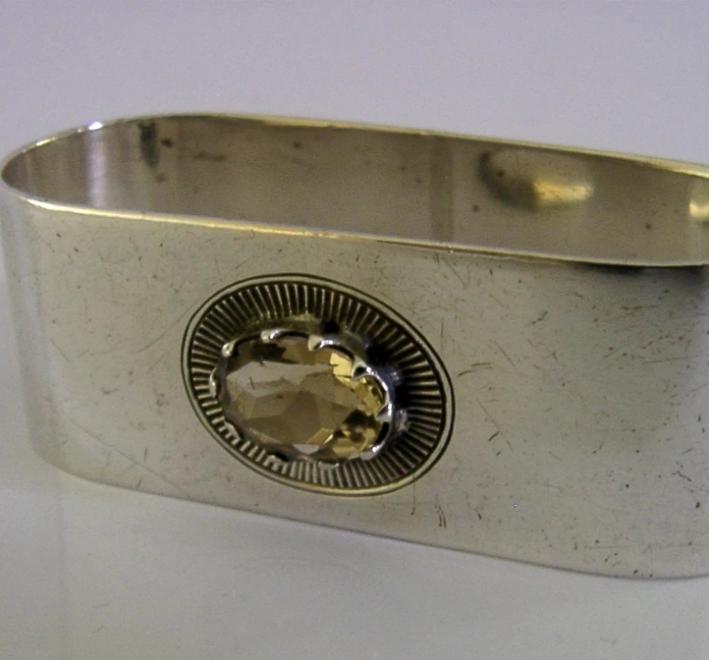 A flat sterling silver napkin ring featuring a central oval faceted citrine gemstone framed by a radiant engraved sunburst motif. View III