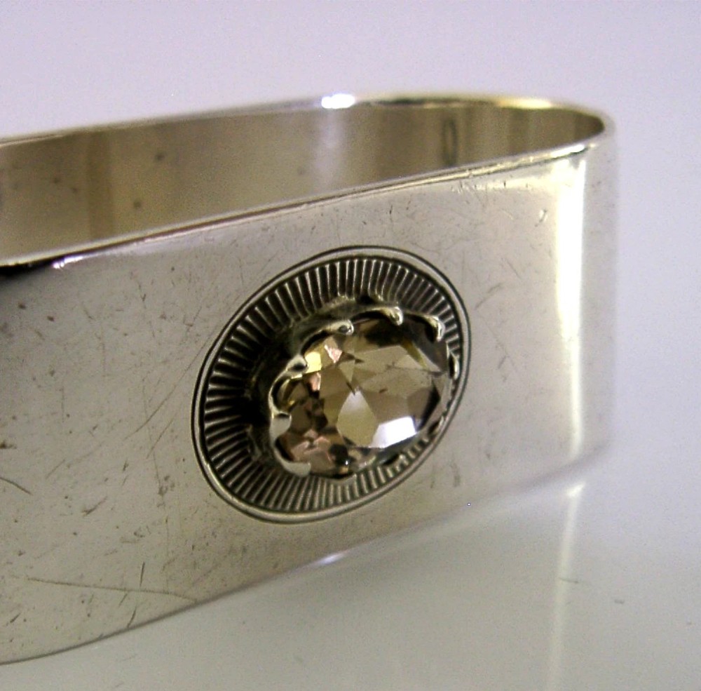 A flat sterling silver napkin ring featuring a central oval faceted citrine gemstone framed by a radiant engraved sunburst motif. View IV