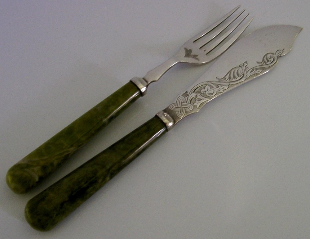 An antique silver-plated fish knife and fork set featuring engraved Celtic knotwork and smooth green marble handles.