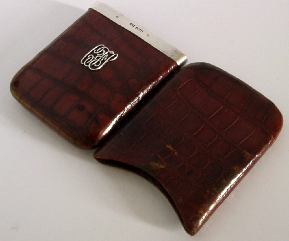 An Edwardian reddish-brown crocodile leather cigar case featuring a sterling silver hallmarked band at the top and an applied silver monogram on the front. View IV