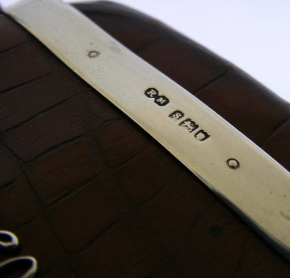 An Edwardian reddish-brown crocodile leather cigar case featuring a sterling silver hallmarked band at the top and an applied silver monogram on the front. View VI