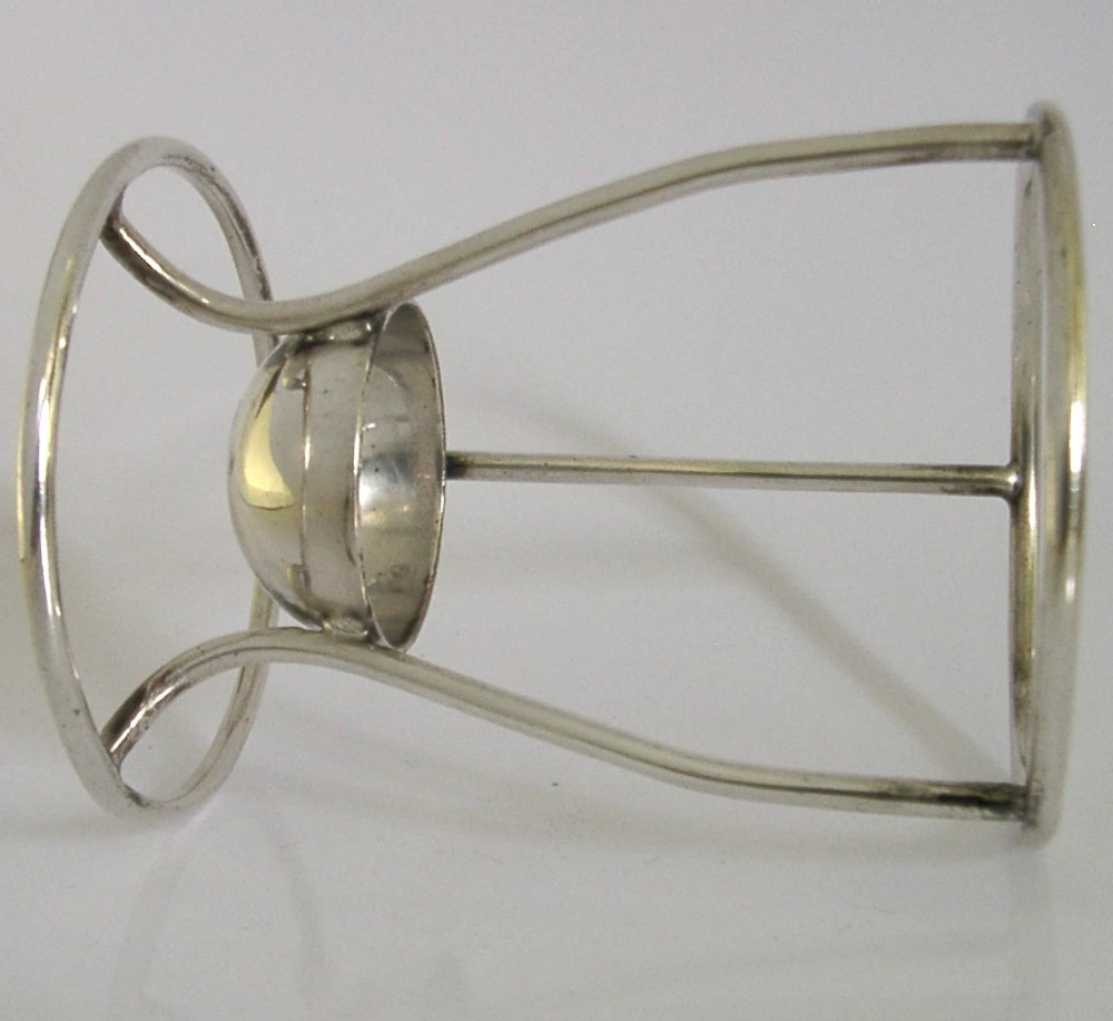 A Victorian silver-plated wirework stand designed to hold a Hamilton torpedo bottle, featuring a circular base, curved uprights, a top ring, and a central cup. View III