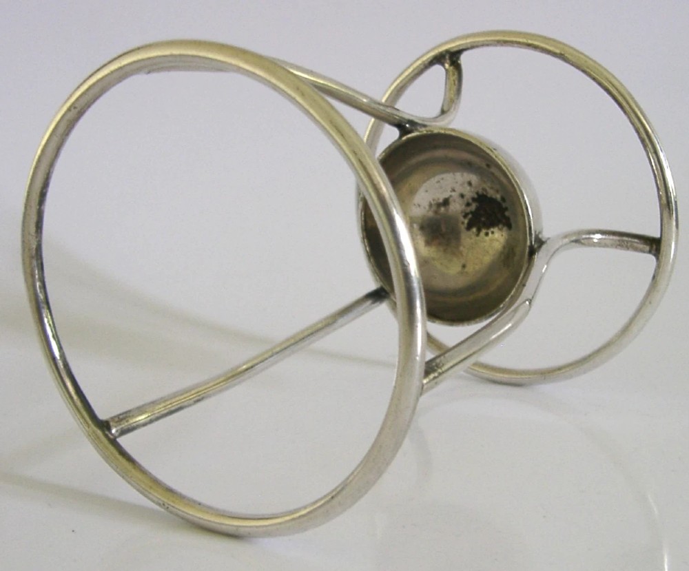 A Victorian silver-plated wirework stand designed to hold a Hamilton torpedo bottle, featuring a circular base, curved uprights, a top ring, and a central cup. View V