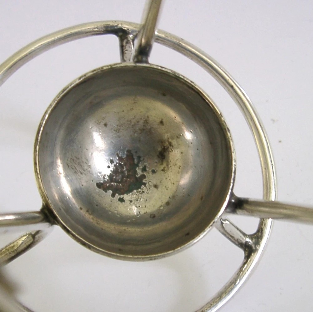 A Victorian silver-plated wirework stand designed to hold a Hamilton torpedo bottle, featuring a circular base, curved uprights, a top ring, and a central cup. View VIII