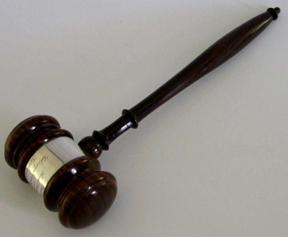 A turned dark hardwood gavel featuring a central sterling silver collar with engraved presentation text. View II