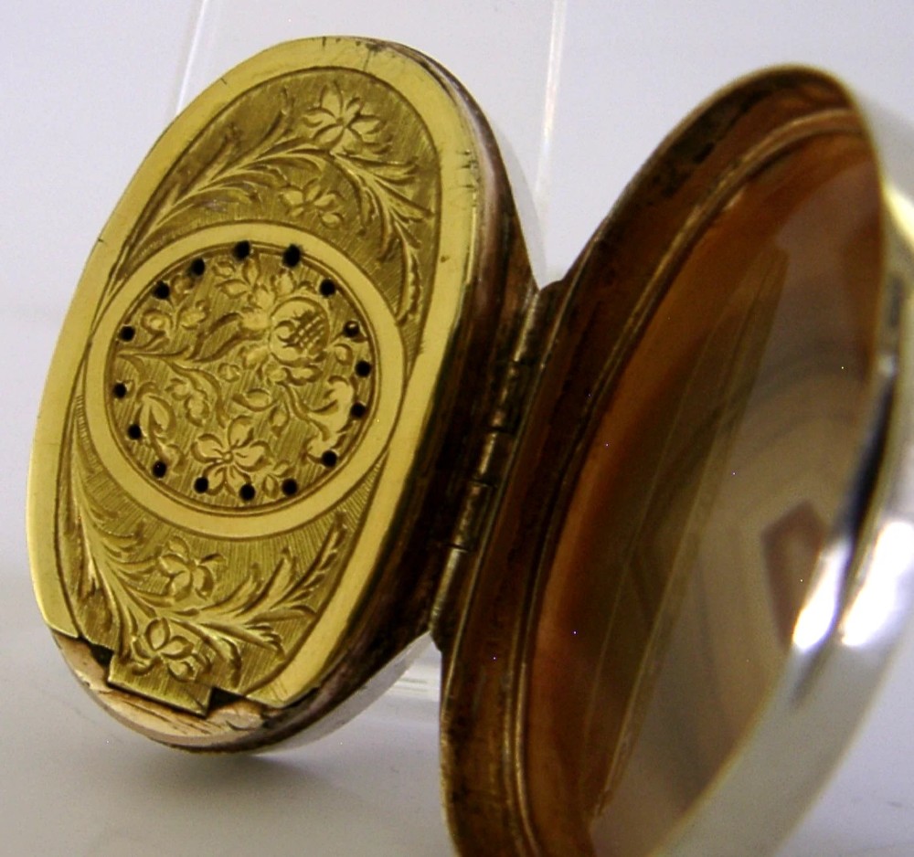 An open Georgian silver oval vinaigrette box featuring a translucent banded agate lid insert and a perforated gold-gilded floral inner grille. View II