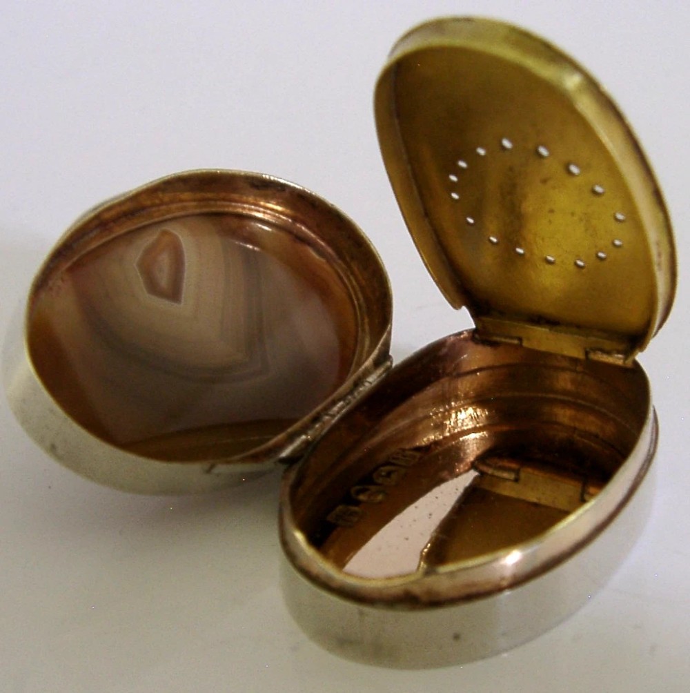 An open Georgian silver oval vinaigrette box featuring a translucent banded agate lid insert and a perforated gold-gilded floral inner grille. View III