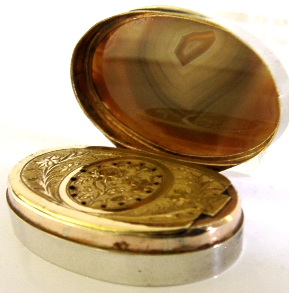 An open Georgian silver oval vinaigrette box featuring a translucent banded agate lid insert and a perforated gold-gilded floral inner grille. View IV