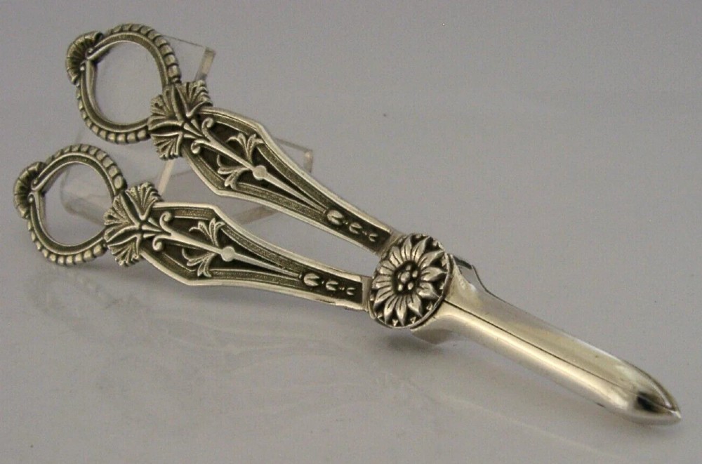 A pair of English sterling silver grape shears featuring Gothic relief carving on the handles and a central floral pivot.