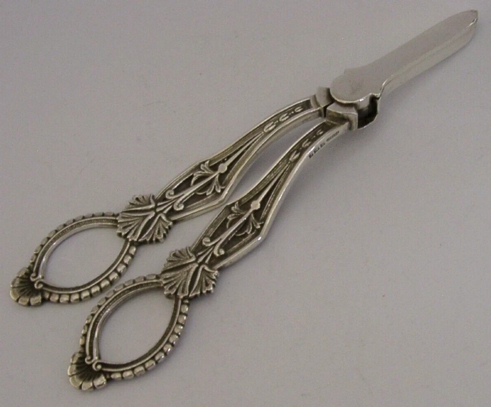 A pair of English sterling silver grape shears featuring Gothic relief carving on the handles and a central floral pivot. View V