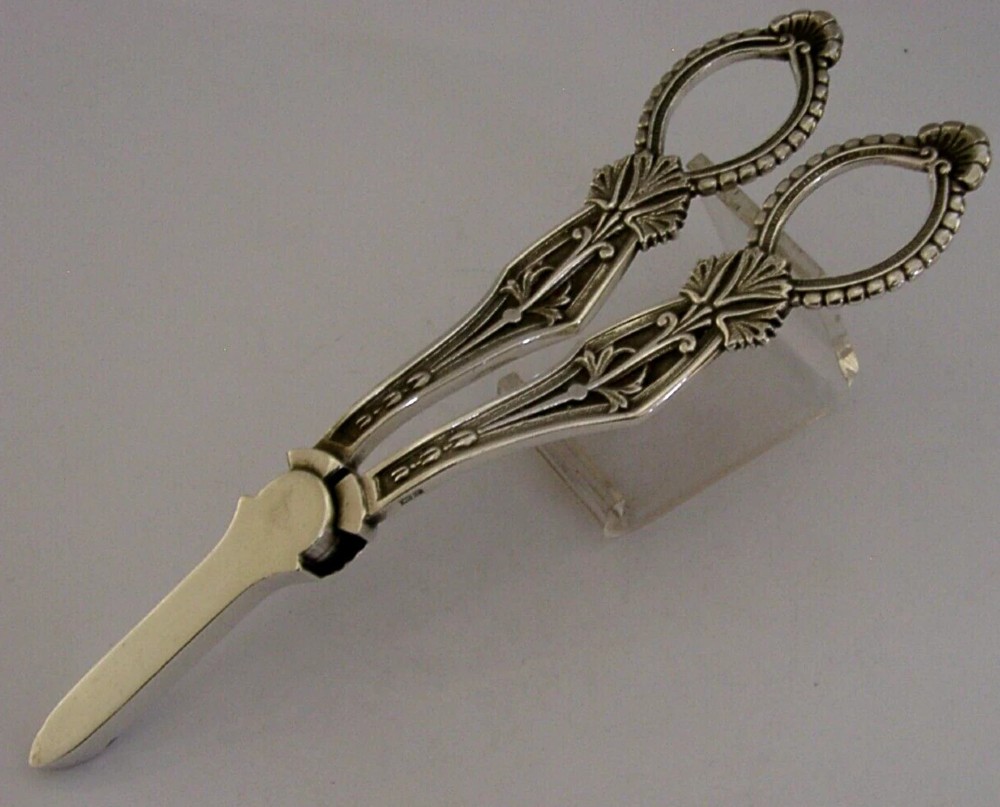 A pair of English sterling silver grape shears featuring Gothic relief carving on the handles and a central floral pivot. View VIII