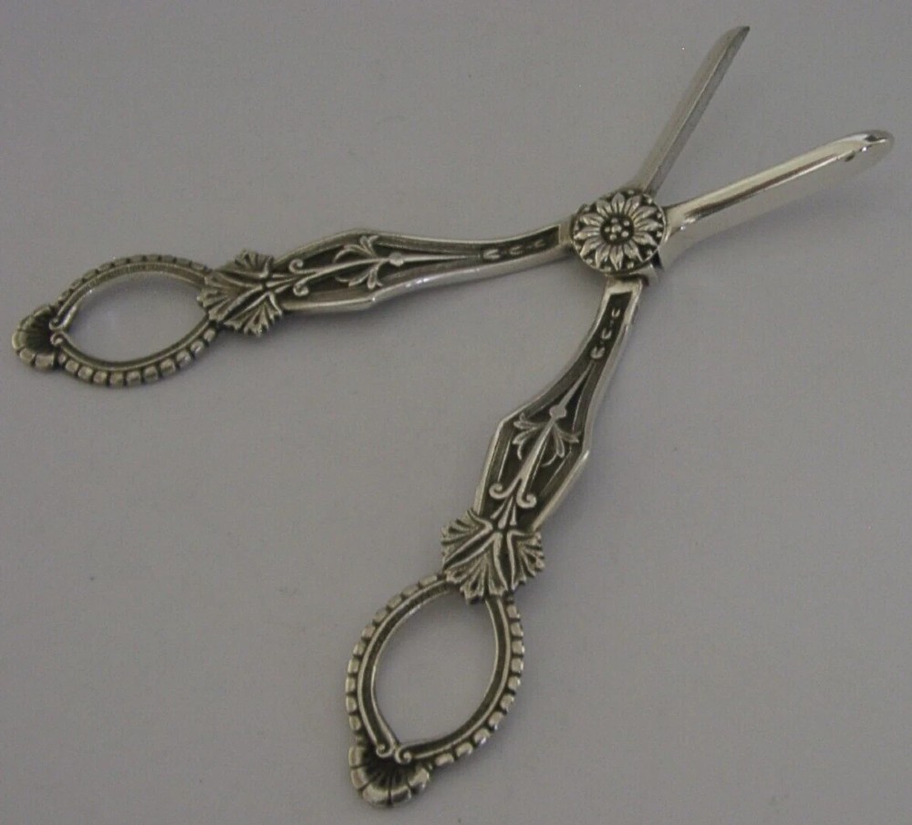 A pair of English sterling silver grape shears featuring Gothic relief carving on the handles and a central floral pivot. View X