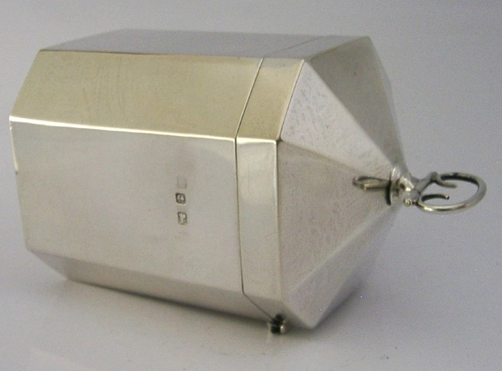 An octagonal sterling silver tea caddy featuring a faceted domed lid, scroll finial, and British hallmarks stamped near the rim. View VII