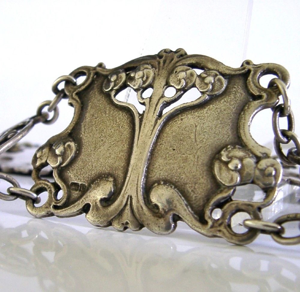 An antique Art Nouveau sterling silver linked waist belt featuring intricate floral panels and a central interlocking buckle. View III