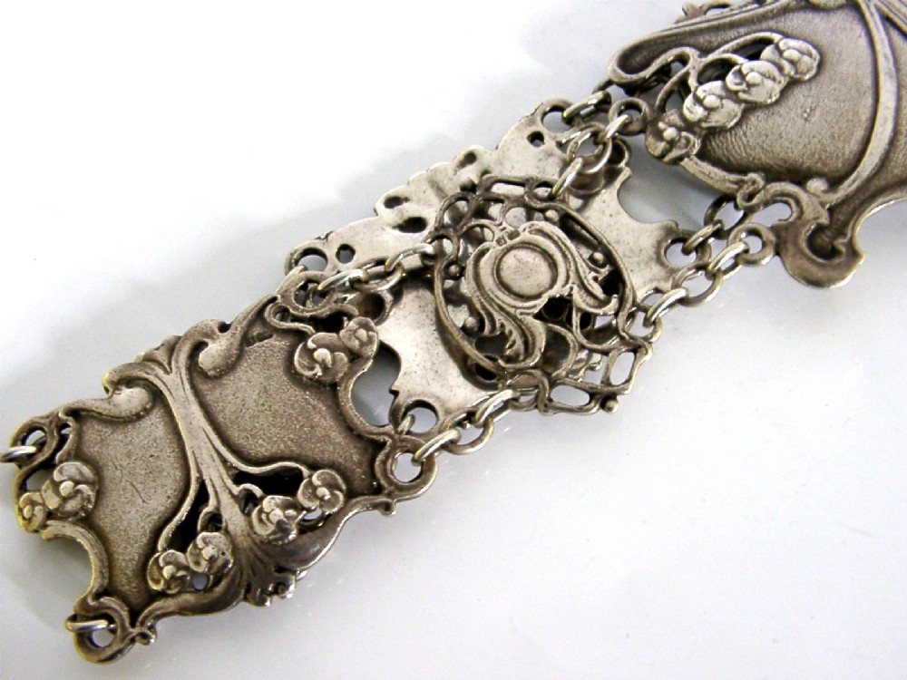 An antique Art Nouveau sterling silver linked waist belt featuring intricate floral panels and a central interlocking buckle. View IV