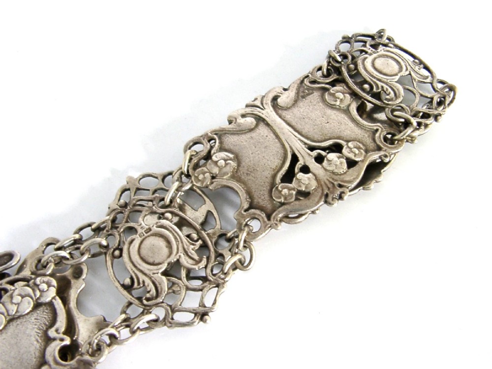 An antique Art Nouveau sterling silver linked waist belt featuring intricate floral panels and a central interlocking buckle. View V
