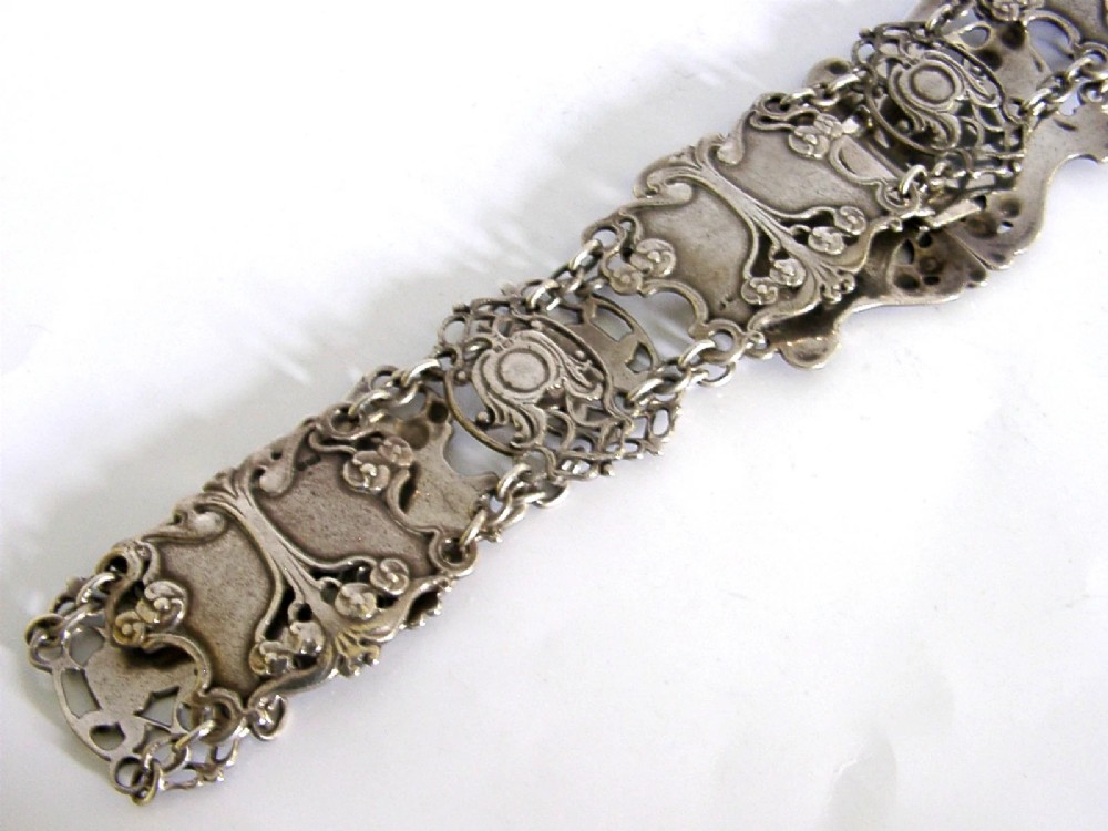 An antique Art Nouveau sterling silver linked waist belt featuring intricate floral panels and a central interlocking buckle. View VI