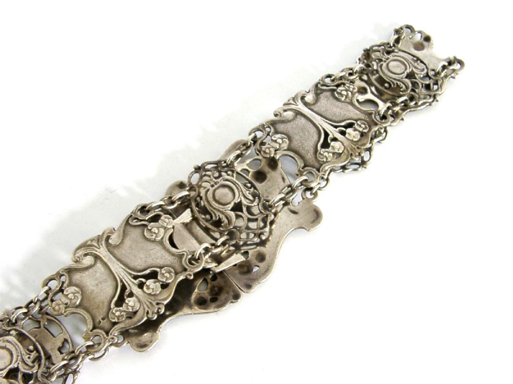 An antique Art Nouveau sterling silver linked waist belt featuring intricate floral panels and a central interlocking buckle. View VII