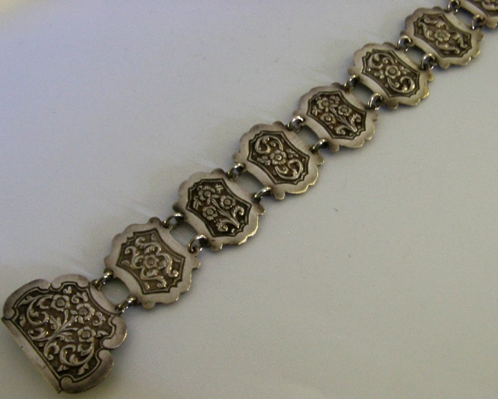 An antique Indian silver belt featuring intricate floral chased link panels and a matching central buckle. View III