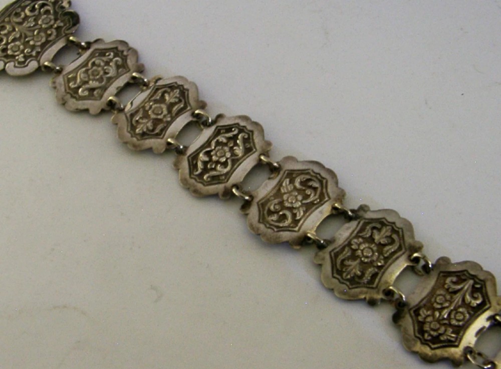 An antique Indian silver belt featuring intricate floral chased link panels and a matching central buckle. View V