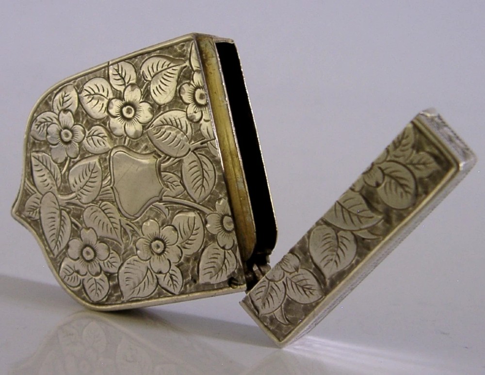 A Victorian shield-shaped sterling silver vesta case engraved with floral motifs and a central vacant cartouche. View V