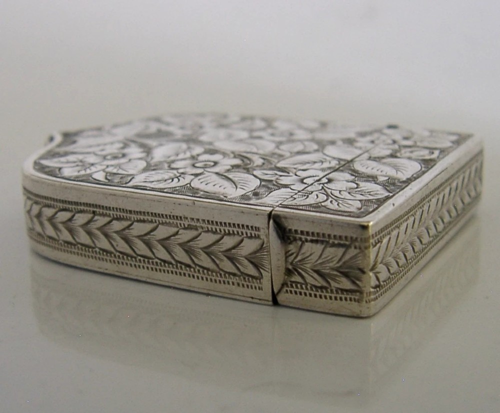 A Victorian shield-shaped sterling silver vesta case engraved with floral motifs and a central vacant cartouche. View VI