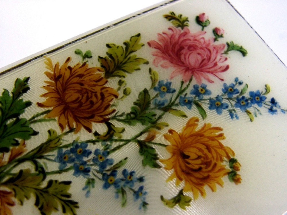 A square sterling silver hinged cigarette case showing an engine-turned textured exterior on one side and a white enamelled panel with hand-painted yellow and pink chrysanthemums on the other. View V