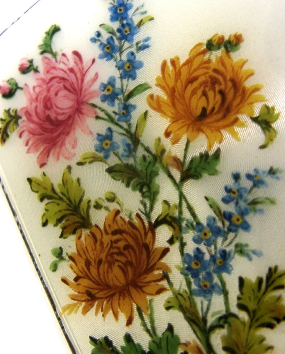 A square sterling silver hinged cigarette case showing an engine-turned textured exterior on one side and a white enamelled panel with hand-painted yellow and pink chrysanthemums on the other. View VII