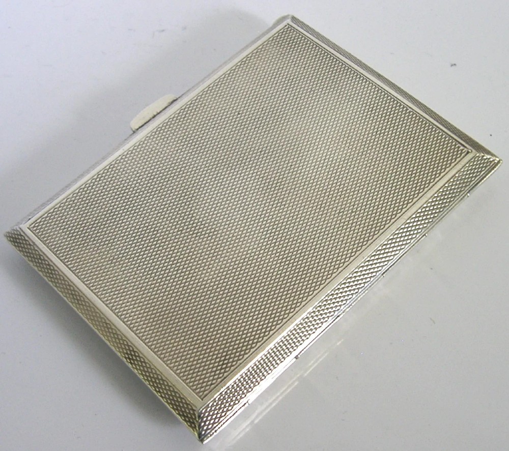 A square sterling silver hinged cigarette case showing an engine-turned textured exterior on one side and a white enamelled panel with hand-painted yellow and pink chrysanthemums on the other. View XII