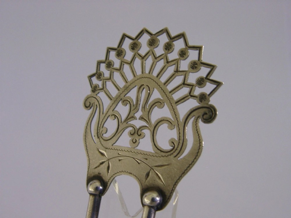 An antique sterling silver two-prong hair slide featuring a fan-shaped pierced crest with scrolling motifs and geometric openwork. View V