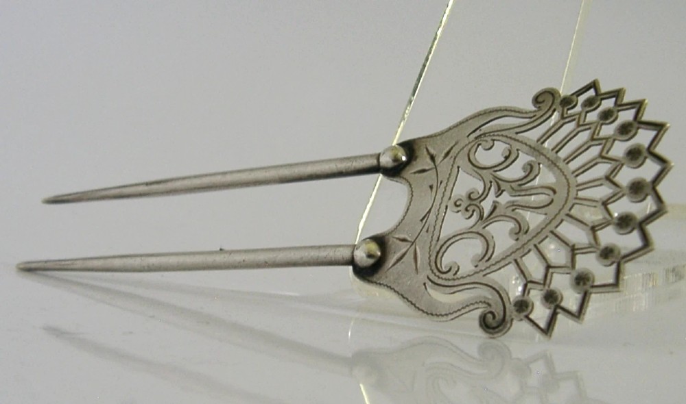 An antique sterling silver two-prong hair slide featuring a fan-shaped pierced crest with scrolling motifs and geometric openwork. View VII