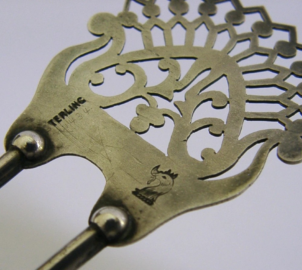 An antique sterling silver two-prong hair slide featuring a fan-shaped pierced crest with scrolling motifs and geometric openwork. View IX