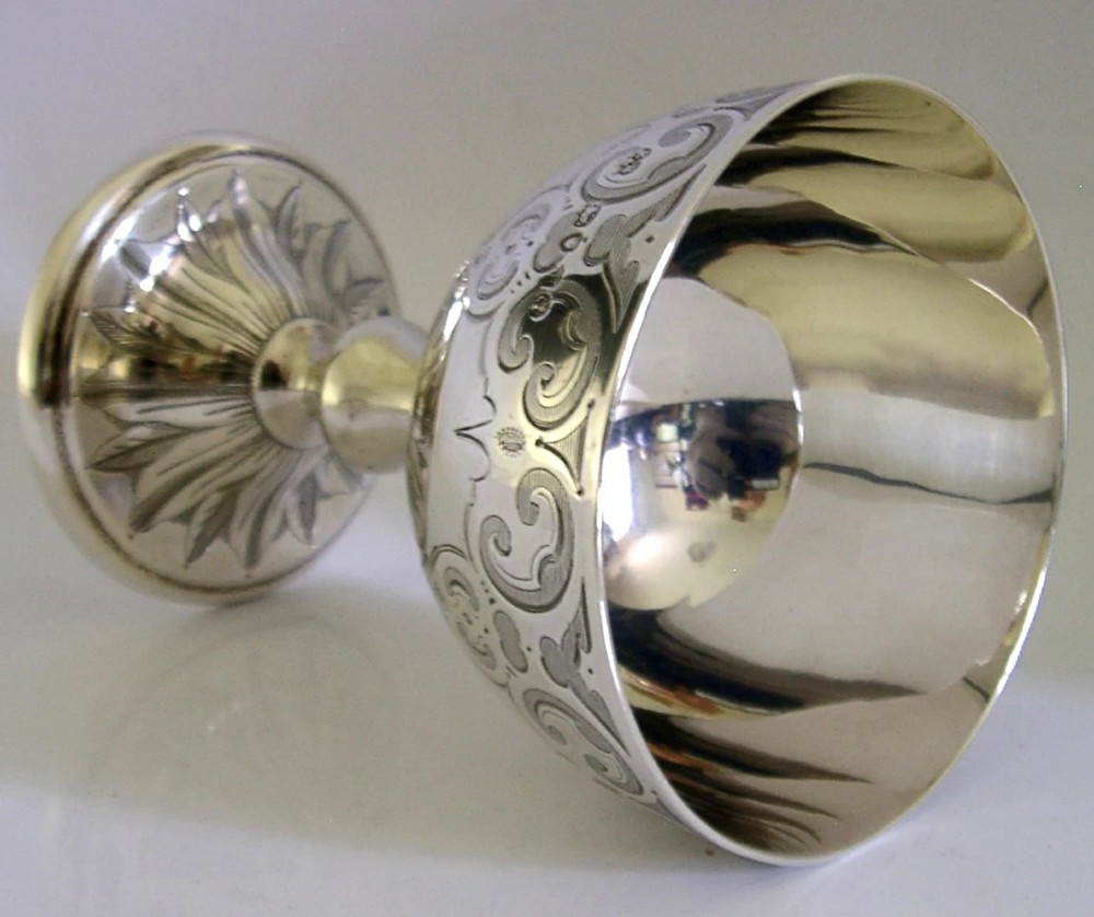 A mid-Victorian sterling silver chalice featuring an engraved scroll pattern around the cup, a central knopped stem, and a leaf-patterned circular base. View III