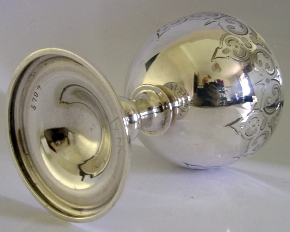 A mid-Victorian sterling silver chalice featuring an engraved scroll pattern around the cup, a central knopped stem, and a leaf-patterned circular base. View VII