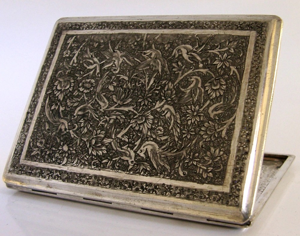 A rectangular solid silver cigarette case featuring hand-chased relief work depicting birds and floral motifs surrounded by a decorative border.