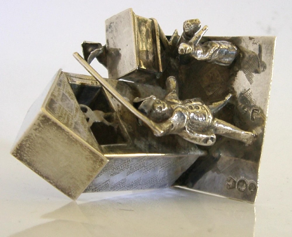 An 833 solid silver miniature model depicting a Punch and Judy puppet show booth with figures, an organ grinder, and a dog on a flat silver base. View VI
