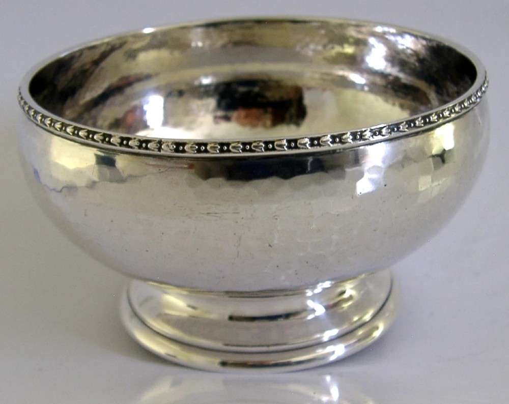 A planished sterling silver bowl featuring a hand-hammered finish, patterned rim, pedestal base, and British hallmarks stamped on the side. View III
