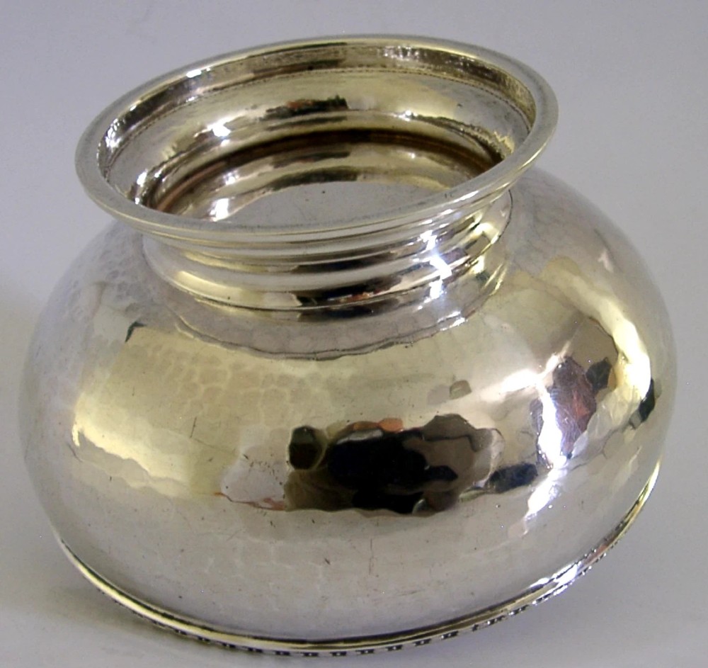 A planished sterling silver bowl featuring a hand-hammered finish, patterned rim, pedestal base, and British hallmarks stamped on the side. View VIII