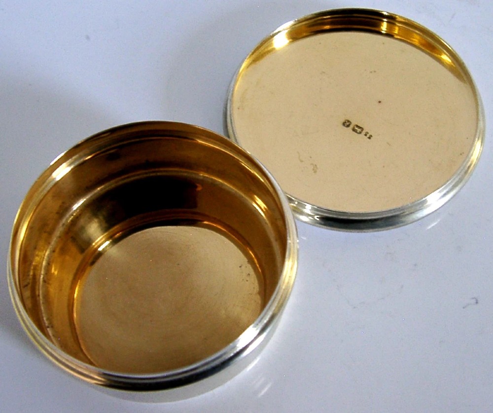A small circular sterling silver pyx box featuring an engraved cross on the cover and a gold gilt interior. View III