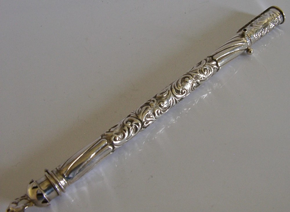 An elongated cylindrical silver Victorian wax holder featuring scrollwork engraving and a camel figure at the terminal.