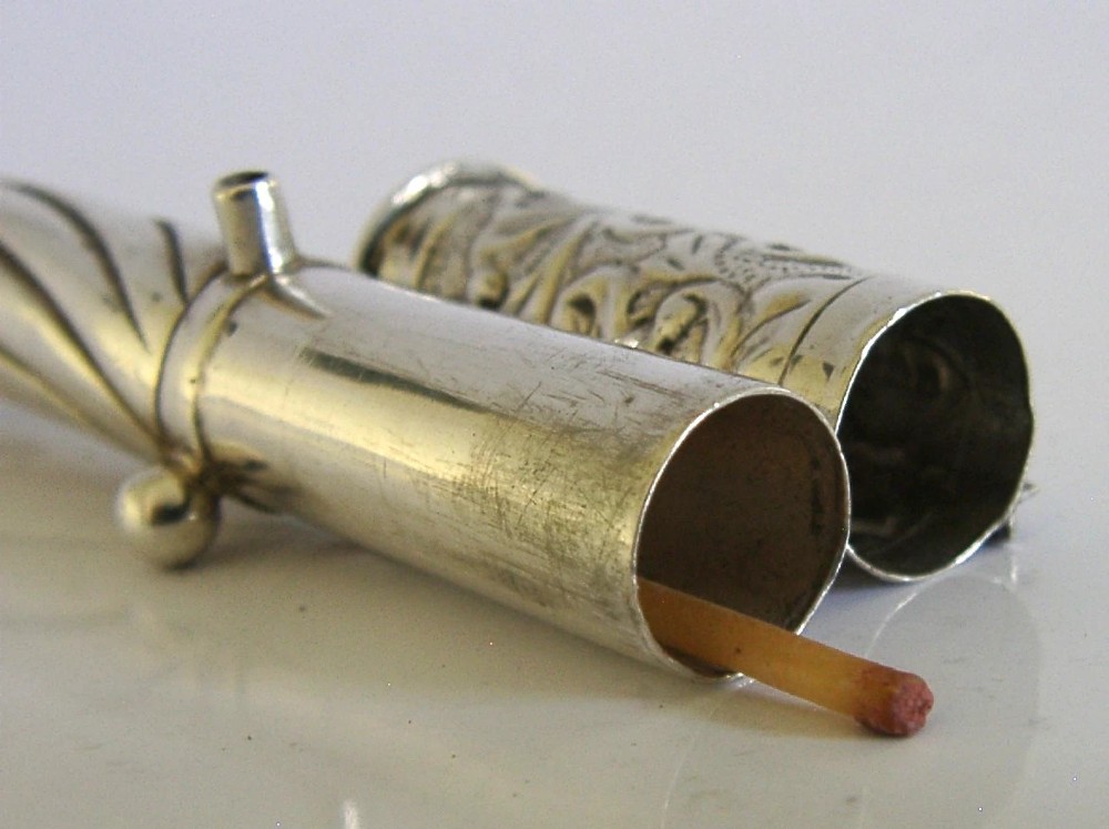 An elongated cylindrical silver Victorian wax holder featuring scrollwork engraving and a camel figure at the terminal. View VIII